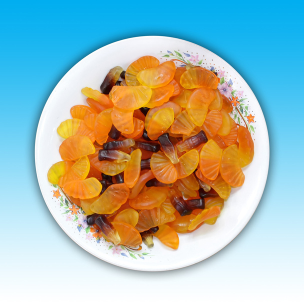 Тарелка апельсинового ломтика и конфеты в форме бутылки колы.
 - Фото, изображение
