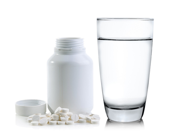 Glas Wasser und Pillen aus Tablettenflasche verschüttet - Foto, Bild