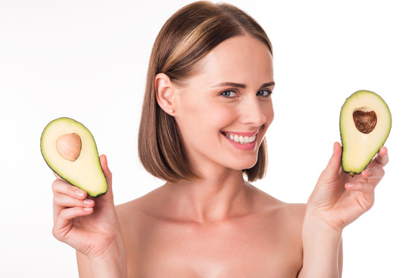 Positive young woman holding avocado - Zdjęcie, obraz