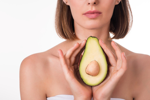 Delighted young woman holding avocado - Foto, Imagen