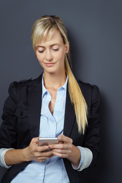 Grinning woman using phone over dark background - Photo, Image
