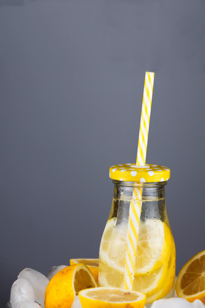 Bevanda alla limonata in bottiglia alla moda con paglia sul ghiaccio
. - Foto, immagini
