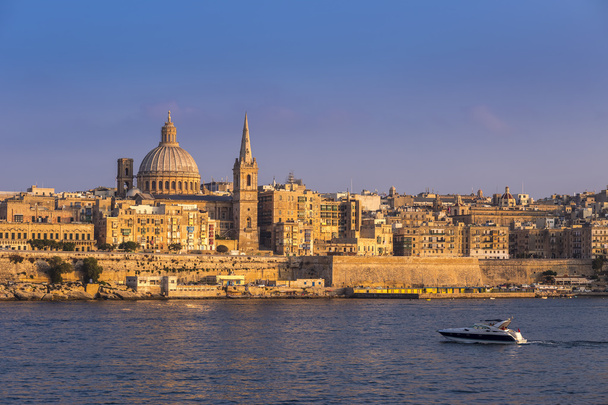 La Valeta, Malta - Motorboat y la famosa Catedral de San Pablo con la antigua ciudad de La Valeta al atardecer
 - Foto, Imagen