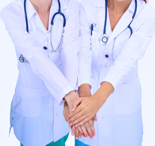 Young woman doctor stacking hands together over white background - Photo, image
