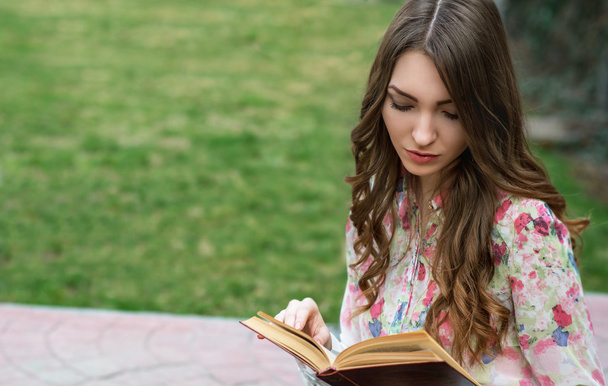 Молодая женщина читает книгу в городском парке. Памятование, фа
 - Фото, изображение