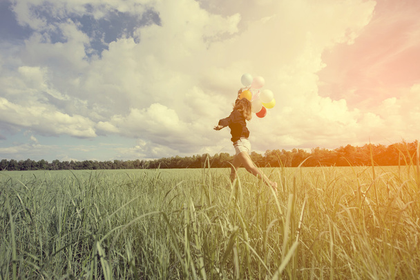  chica caminando en un campo dejando ir un montón de globos hechos con un efecto de filtro retro instagram vintage
 - Foto, Imagen