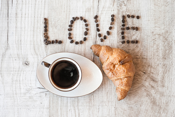 Cup of coffee with croissant on wooden background. title i love coffee. - Valokuva, kuva