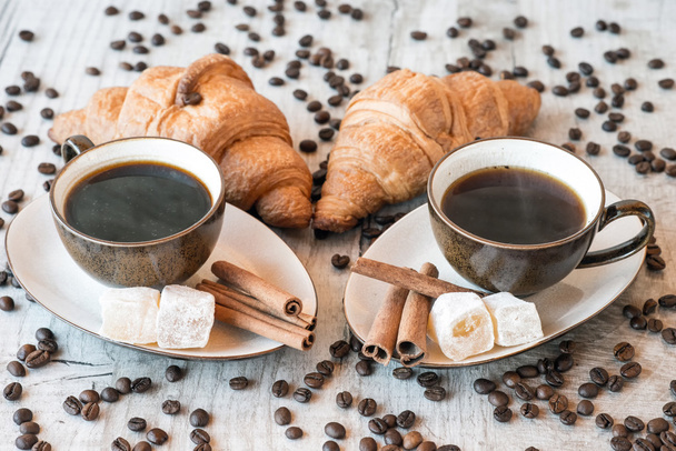 Šálek kávy s zrna, croissant, turecký med a skořice hole na dřevěné pozadí - Fotografie, Obrázek