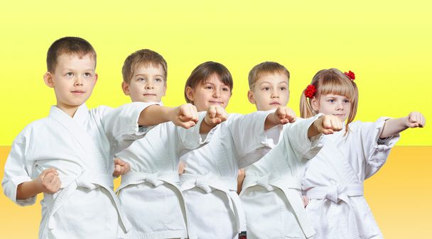 Vijf kleine atleten hits per punch arm op een gele achtergrond - Foto, afbeelding