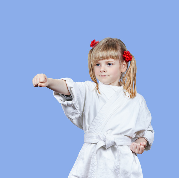 On a blue background sportswoman beats punch arm - Фото, изображение