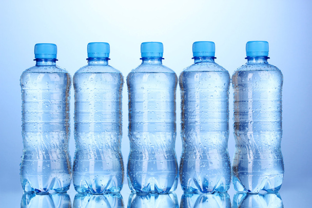 Plastic bottles of water on blue background - Foto, Imagen