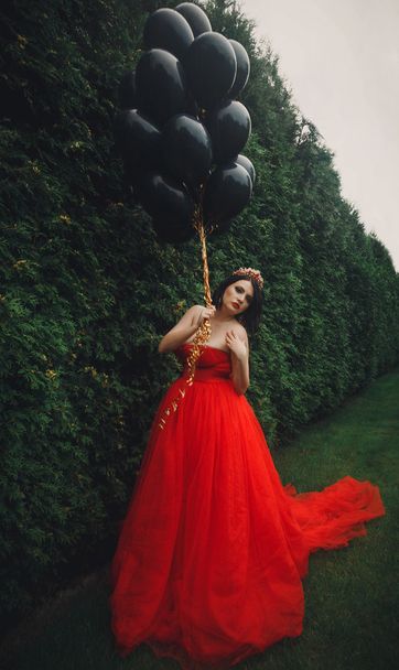 Gorgeous woman in red dress with black balloons - Foto, Bild