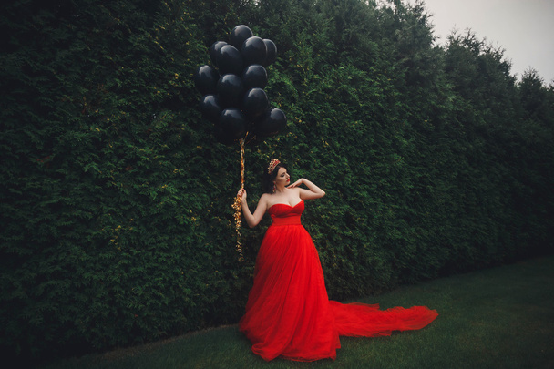 Πανέμορφη γυναίκα σε κόκκινο φόρεμα με τα μαύρα μπαλόνια - Φωτογραφία, εικόνα