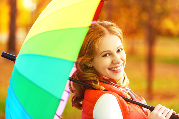 ευτυχισμένη γυναίκα με πολύχρωμα ομπρέλα ουράνιο τόξο υπό βροχή στην παράγρ - Φωτογραφία, εικόνα