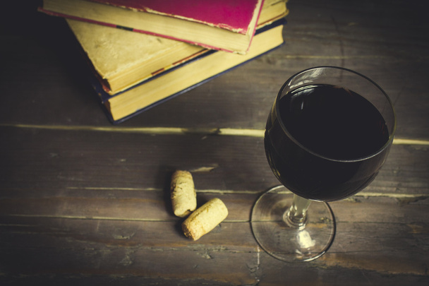 Red wine glass and old open book on wooden table - Photo, Image