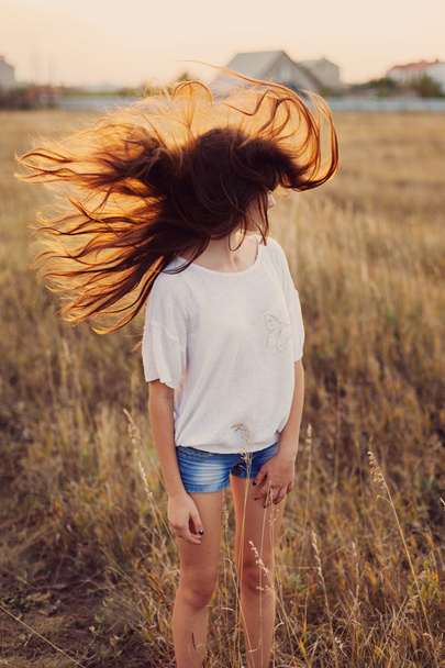 Young girl with long brown hair stay at the meadow.  - Photo, Image