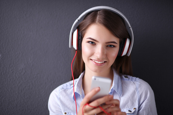 Smiling girl with headphones sitting on the floor near wall - Foto, Imagem