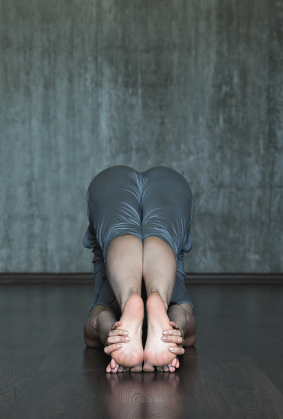 Young woman practicing yoga on a background of gray concrete wall. - Foto, Imagen
