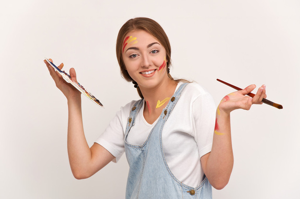 mooie jonge kunstenaar holding een palet en penselen. - Foto, afbeelding