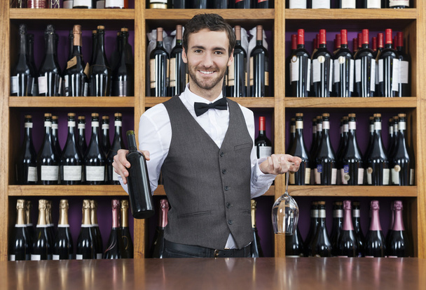 Bartender Holding Red Wine Bottle And Glass In Shop - Zdjęcie, obraz