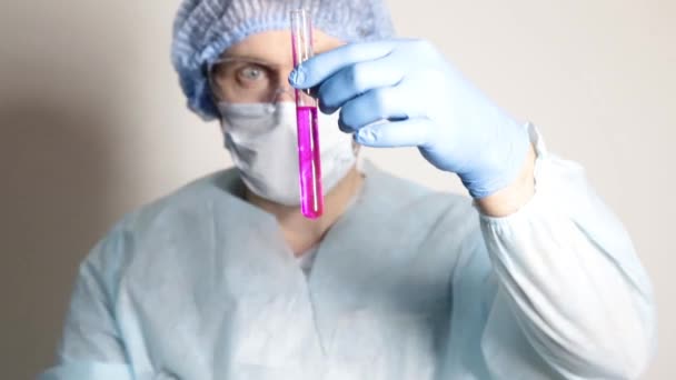 Wissenschaftler Arzt in medizinischer Uniform, hält Fläschchen und beobachtet den Fortschritt des Experiments - Filmmaterial, Video