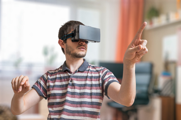 L'uomo eccitato indossa cuffie realtà virtuale e sta toccando qualcosa
. - Foto, immagini