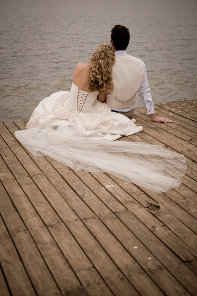 Bride and groom relaxing on wooden dock - Фото, изображение