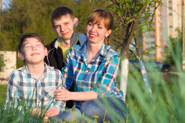 Family sitting on the grass in the park - Zdjęcie, obraz