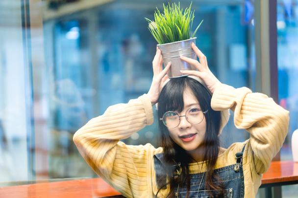 Asiática chica holding planta pot
 - Foto, Imagen
