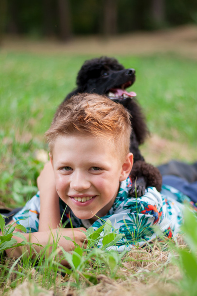 chico con un caniche negro en la naturaleza
 - Foto, Imagen