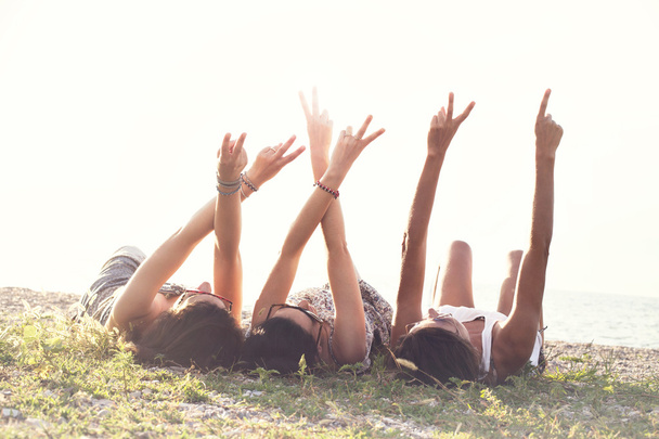 giovani donne distese nel prato alzano le braccia in segno di amicizia
 - Foto, immagini