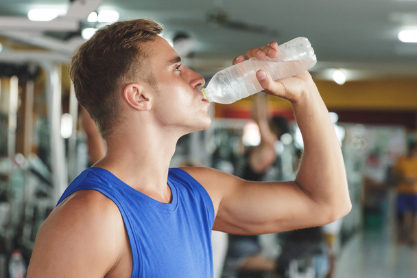 man drinking mineral water at gym - Photo, image