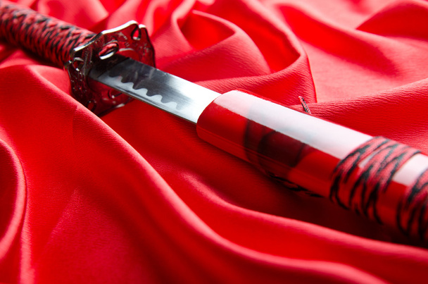 Japon kılıcı takana kırmızı saten zemin üzerine - Fotoğraf, Görsel
