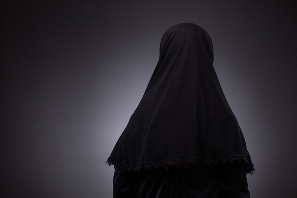 Muslim woman in black dress against dark background - Photo, Image