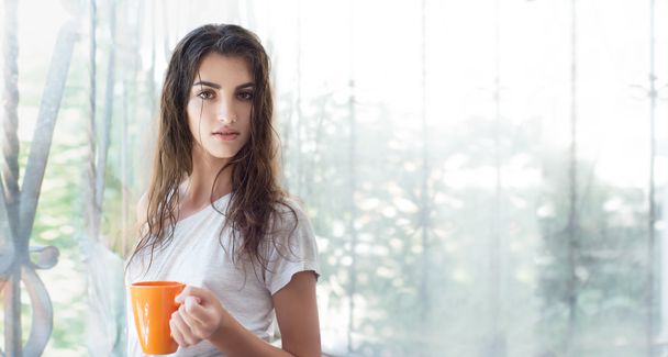 Όμορφη νεαρή γυναίκα με το πρωινό φλιτζάνι ζεστό ρόφημα.  - Φωτογραφία, εικόνα