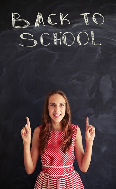 Teenage girl against chalk inscription on blackboard showing for - Foto, Imagem