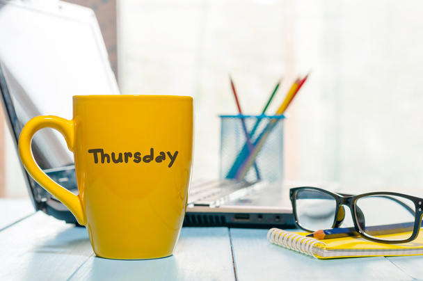 Jeudi mot écrit sur la tasse jaune de café au bureau maorning lieu de travail avec ordinateur portable et lunettes
 - Photo, image