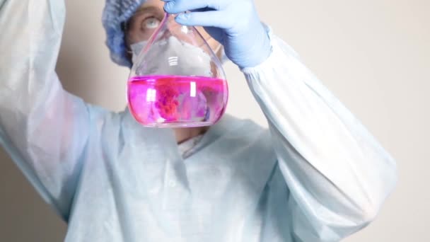 scientist doctor in medical uniform, holding flask and watching the progress of experiment - Footage, Video