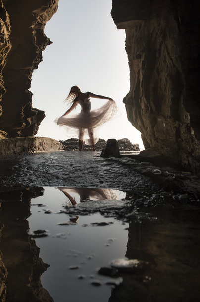Woman dancing under rocky archway - Valokuva, kuva