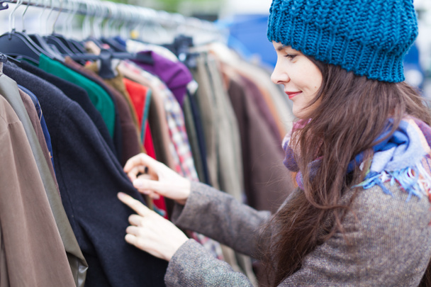 Женщина выбирает одежду на блошином рынке
. - Фото, изображение
