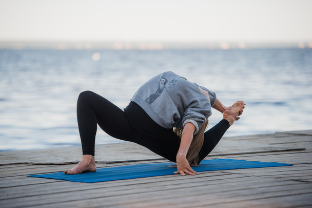 junge Sportlerin praktiziert Yoga am Strand - Foto, Bild