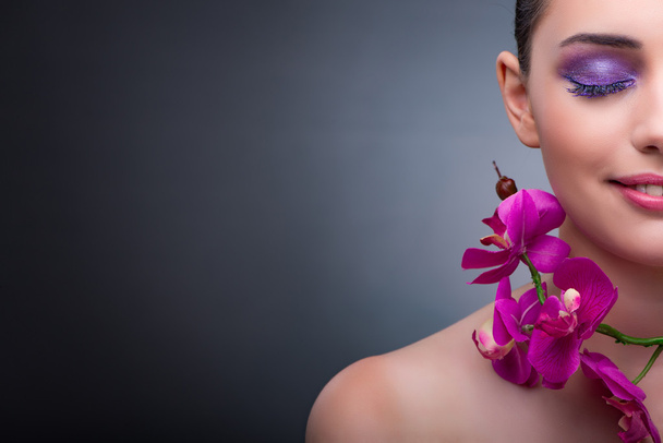 Young woman in beauty concept with orchid flower - Foto, afbeelding