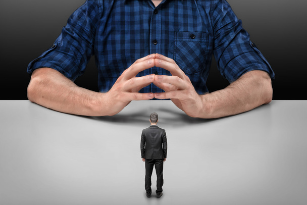 Businessman stands in front of big man sitting with his fingers clasped - Foto, immagini