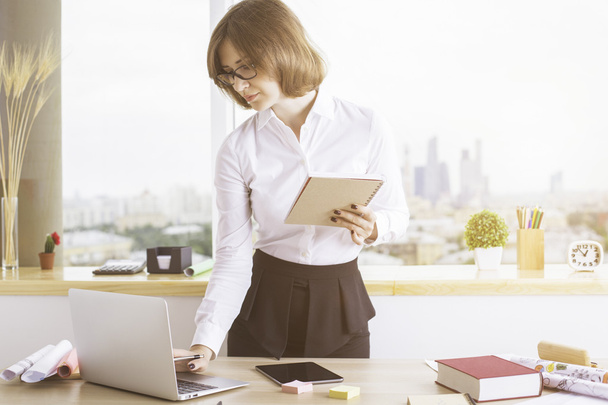 Businesswoman with notepad using laptop - Valokuva, kuva