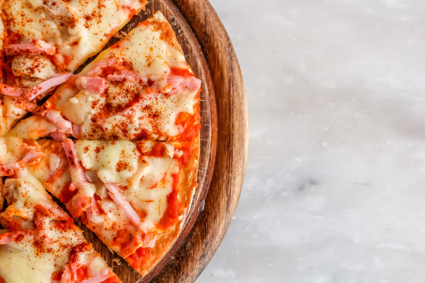 Hot pizza slice with melting cheese on a white granite stone table. - Photo, Image
