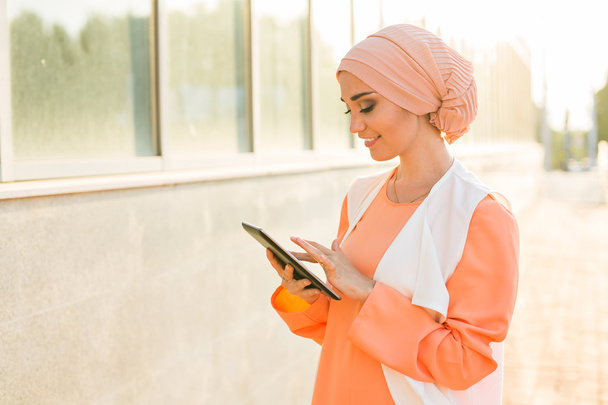 タブレット コンピューターを屋外でモダンなアラビアのイスラム教徒の女性 - 写真・画像