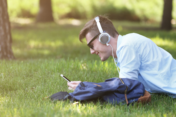 man lying on grass and listening music - Foto, Imagen