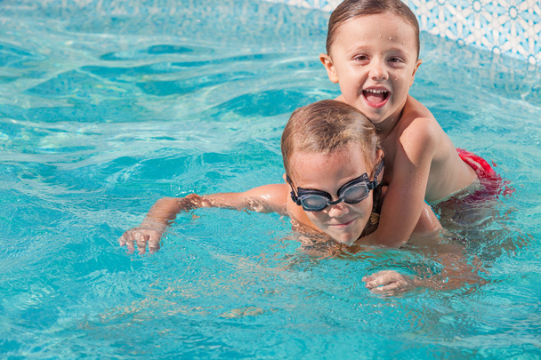 Dvě šťastné děti si hrají na plavecký bazén v denní době. - Fotografie, Obrázek