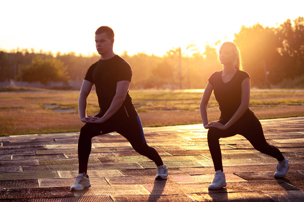 Silhouettes of young sporty man and woman outdoors - Φωτογραφία, εικόνα