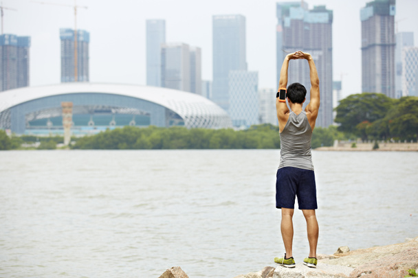 jeune asiatique jogger étirement bras avant de courir
 - Photo, image